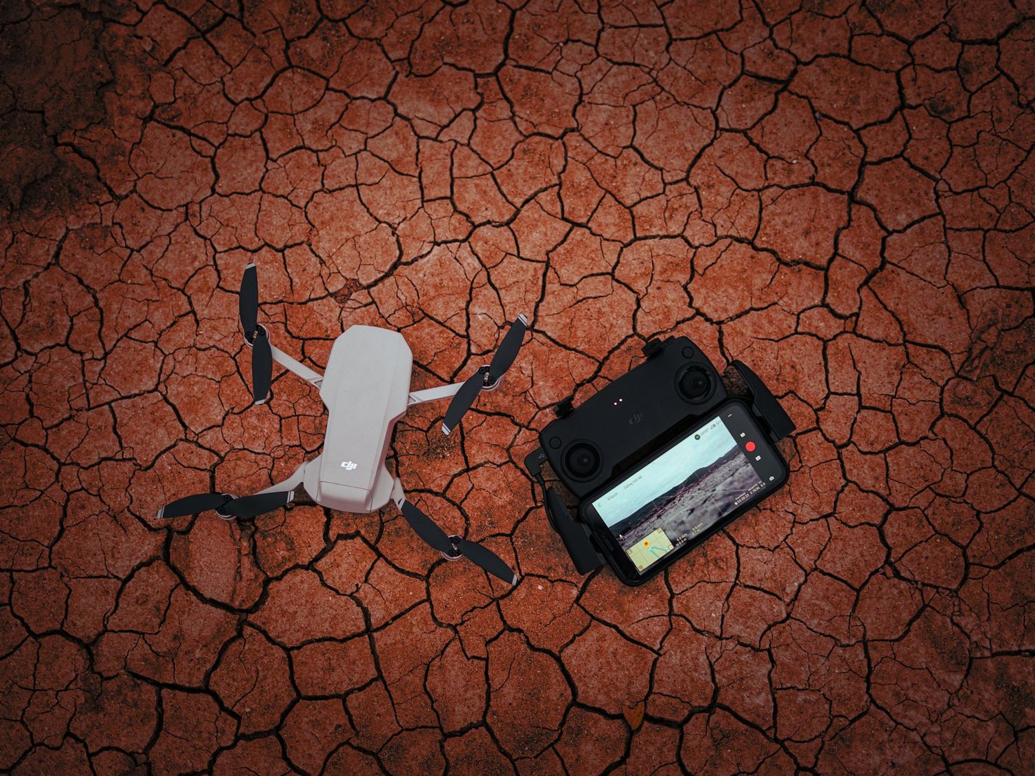 Drone et télécommande posés sur un sol aride craquelé